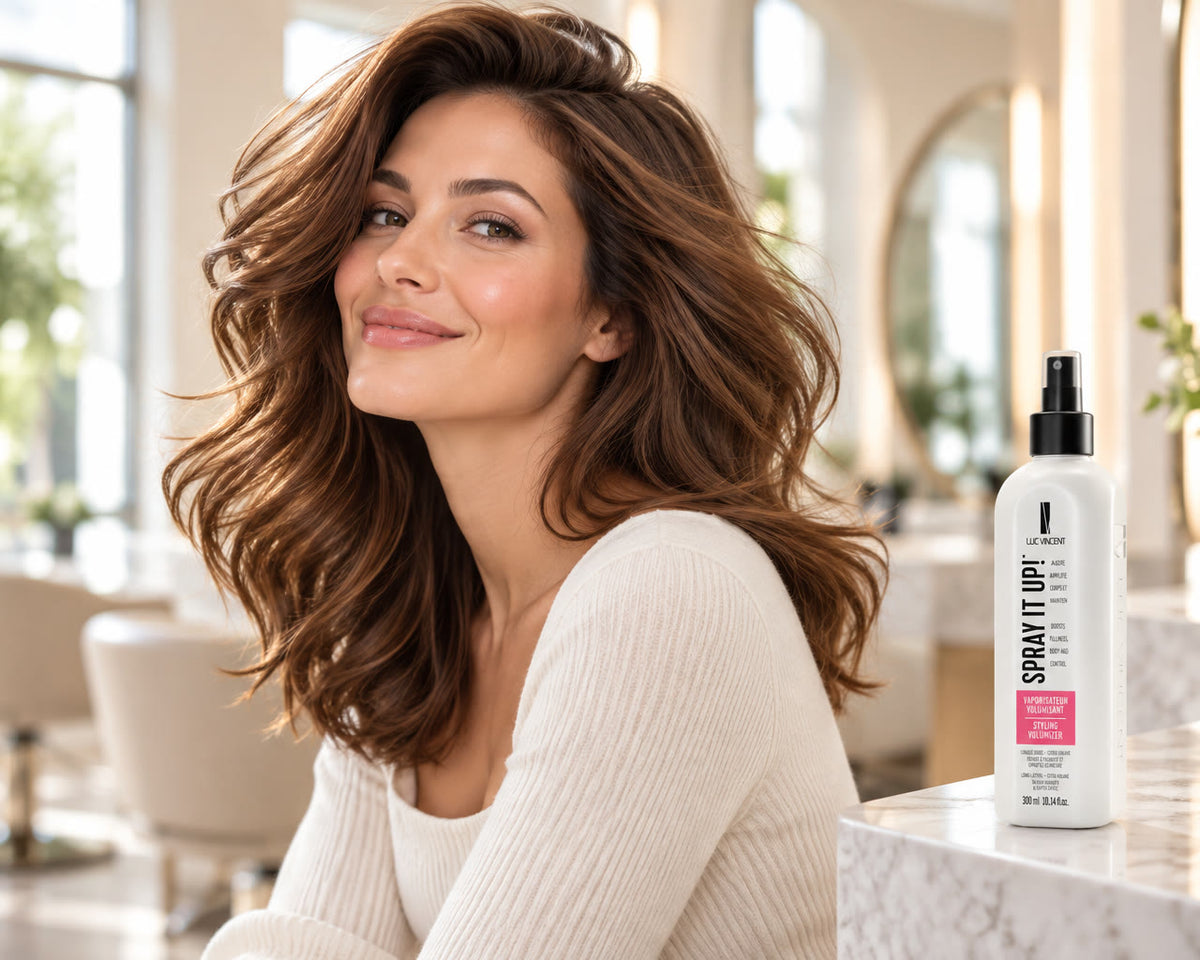 Femme aux cheveux volumineux et brillants dans un salon lumineux, à côté du flacon Spray it up!